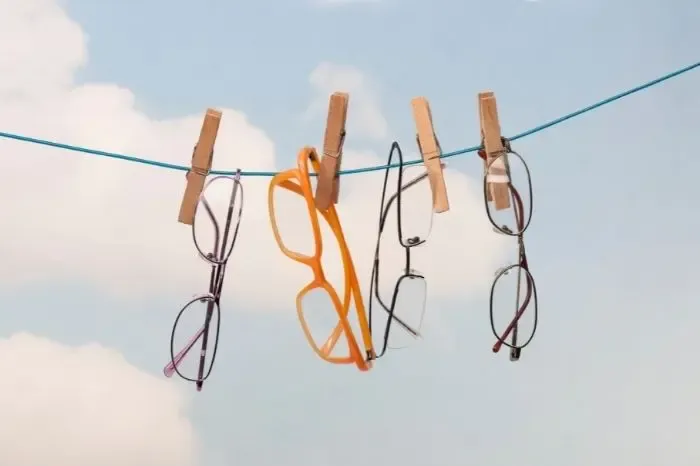 Lunettes suspendues à un fil à linge, illustrant un séchage ou un nettoyage original des montures