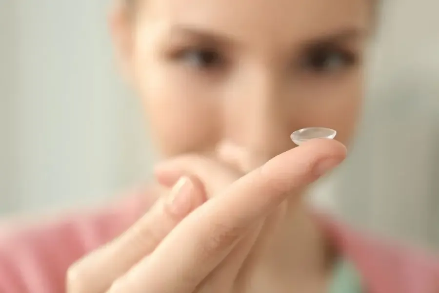 Femme inspectant sa lentille de contact avant de la poser sur son œil pour assurer confort et sécurité