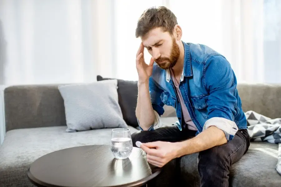 Homme souffrant d’une migraine ophtalmique prenant un médicament pour soulager la douleur et l’inconfort visuel