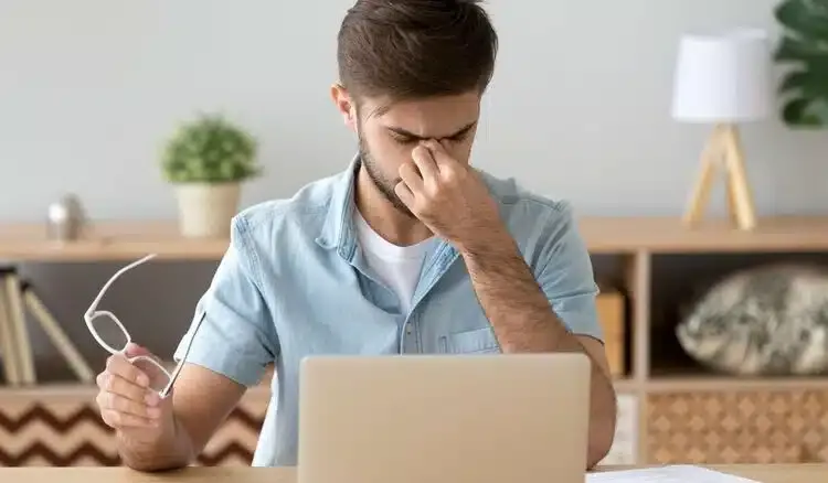 Homme devant son ordinateur sans porter ses lunettes avec verres anti-reflets et protection contre la lumière bleue