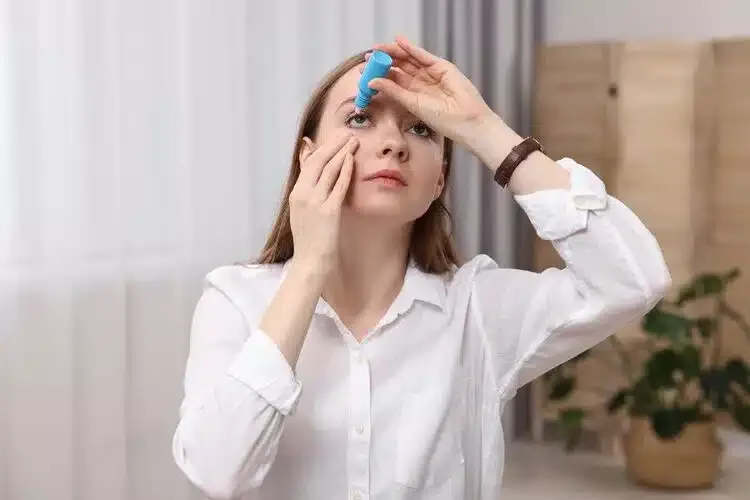 Femme mettant des gouttes dans l’œil pour hydrater et soulager la sécheresse oculaire