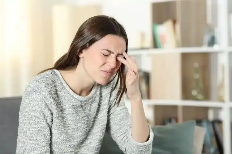 Femme avec une lentille de contact coincée dans l’œil provoquant inconfort et irritation