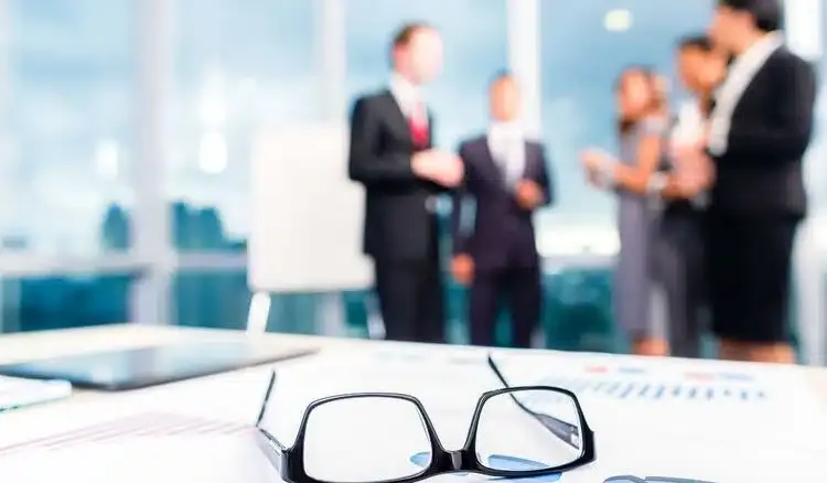 Paire de lunettes posée sur un bureau lors d’une réunion de travail