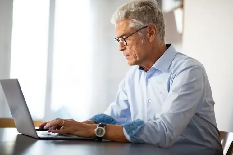 Homme portant des lunettes anti-lumière bleue pour travailler devant son ordinateur et réduire la fatigue oculaire
